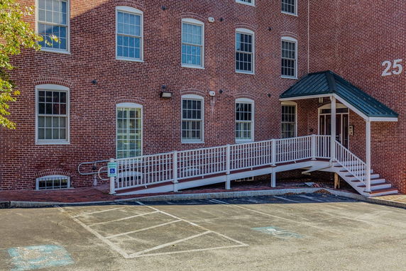 Front view of a brick building with multiple windows and an entrance ramp.