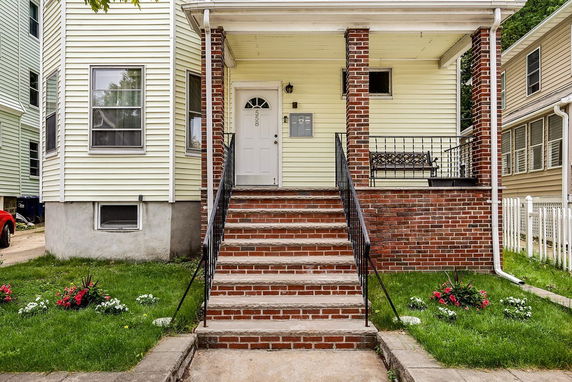 Front view of a house with a brick porch and stairs.