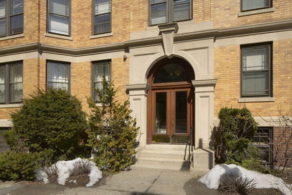 Entrance view of a multi-story brick building with a prominent archway and steps.