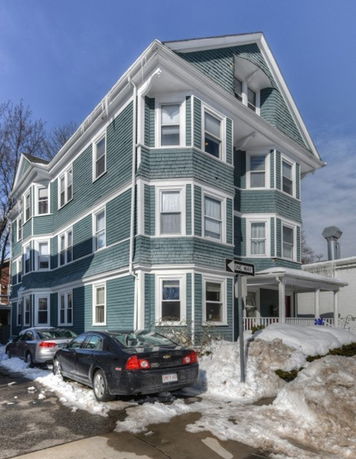 Front view of a three-story house with multiple windows and a porch.