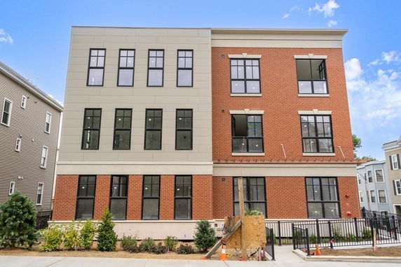 Front view of a three-story building with a brick and panel facade.