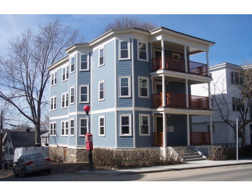 Front view of a multi-story residential building with blue siding and multiple balconies.