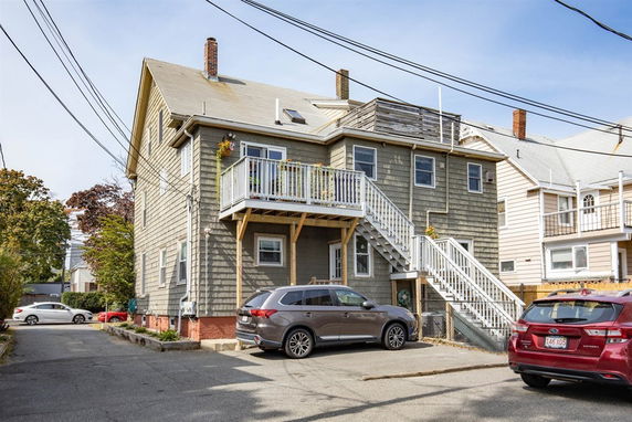 Back view of a multi-story house with external staircase and small deck.