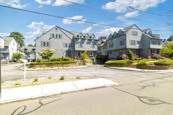 Front view of a multi-story residential building complex with gabled roofs and multiple entrances.