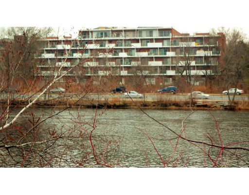 Front view of a multi-story apartment building across a body of water.