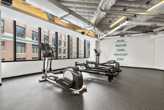Interior view of a fitness area with exercise equipment and motivational wall text.