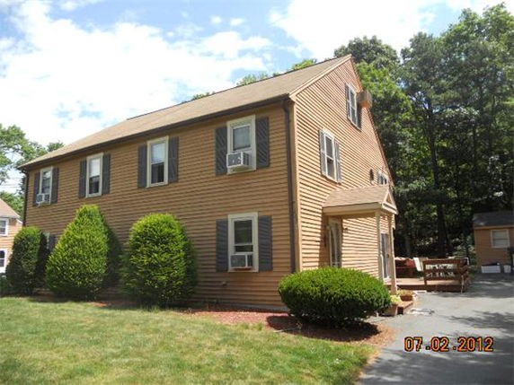 Front view of a two-story house with brown siding and multiple windows.
