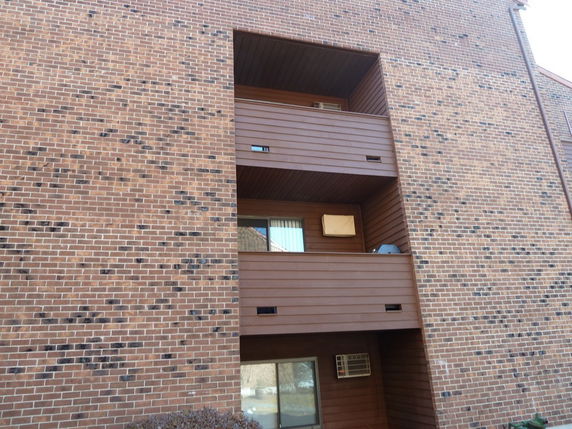 Front view of a multi-story building with brick exterior and balconies.