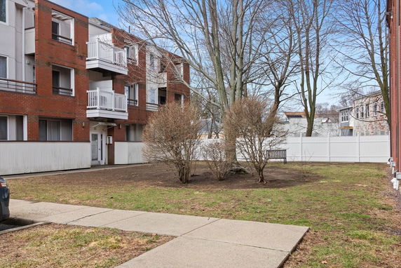 Front view of a three-story brick apartment building with balconies.
