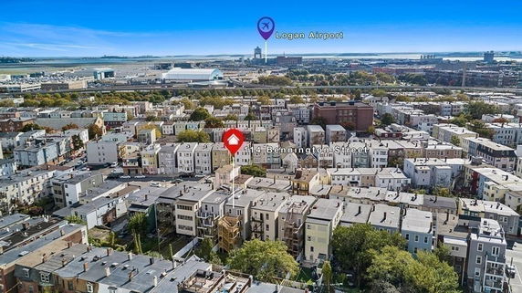 Aerial view of a neighborhood with multiple residential buildings and Logan Airport in the distance.