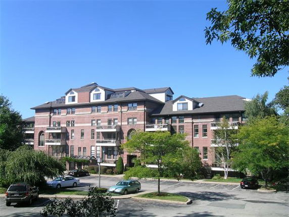 Front view of a multi-story brick building with balconies and parking area.