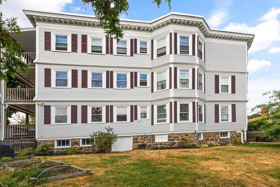 Front view of a multi-story residential building with bay windows and brick foundation.