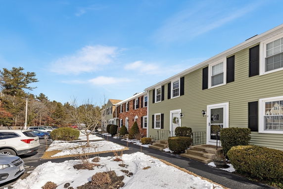 Front view of a row of two-story townhouse buildings with different colored sidings.