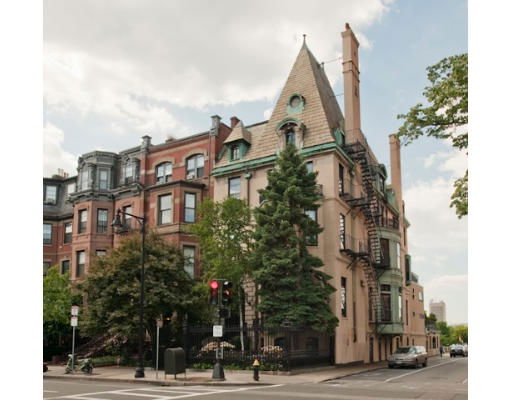 Front view of a multi-story building with a triangular roof and fire escapes.