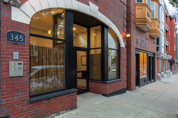 Front view of a brick building with large windows and a signage for Davis Hairdressing.