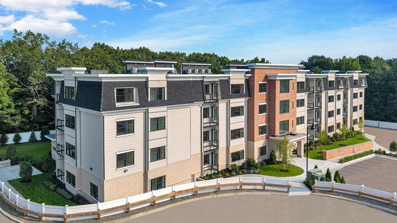 Front view of a multi-story apartment building with white and brick facade.