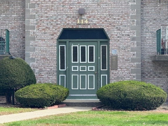 Front view of a building entrance with green doors and brick exterior.