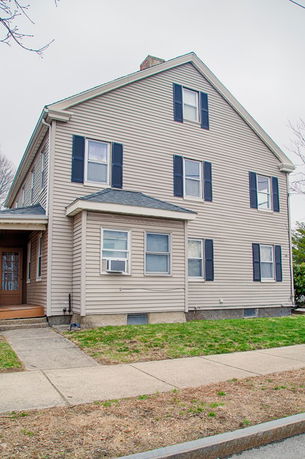 Front view of a two-story house with beige siding and black shutters.