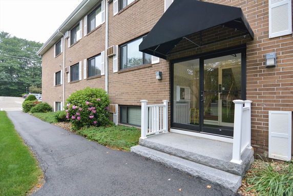 Front view of a multi-story brick building with black awning over the entrance.