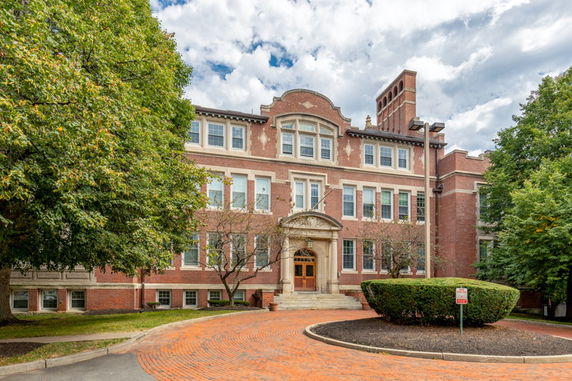 Front view of a large brick building with multiple windows and a central entrance.