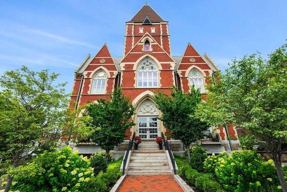Front view of a multi-story brick building with pointed arch windows and a central tower.
