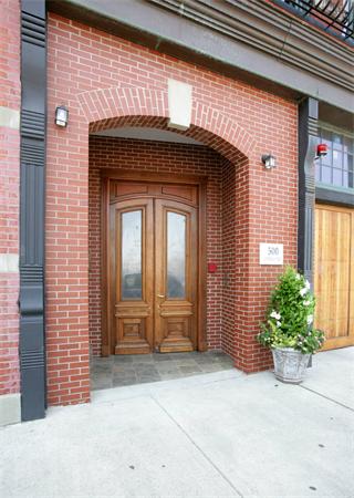 Front view of a brick building entrance with a wooden door.