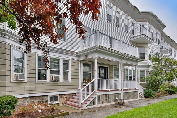 Front view of a multi-story residential building with balconies and stairs leading to the entrance.