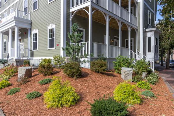 Corner view of a multi-story house with covered balconies and green siding.