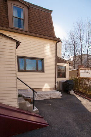 Rear view of a multi-story house with a sloped roof and brown siding.