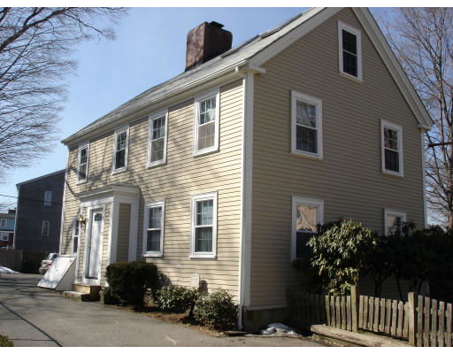 Front view of a two-story house with beige siding and a chimney.