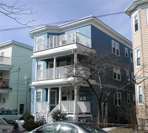 Front view of a three-story blue house with multiple balconies and a white porch.