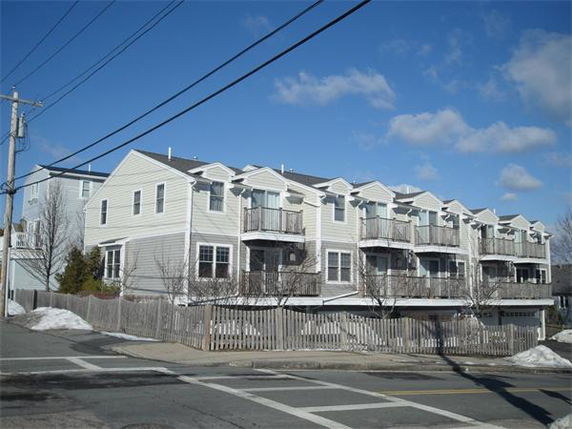 Front view of a row of townhouses with balconies and garages.