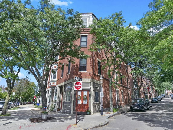 Front view of a corner three-story brick building with large windows.