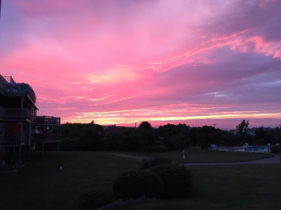 Panoramic view of a sunset with houses and a swimming pool in the landscape.