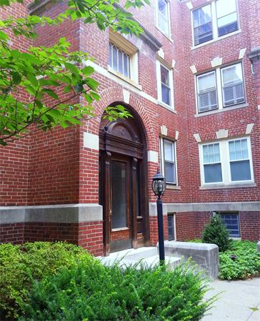 Front view of a multi-story brick building with arched entrance.