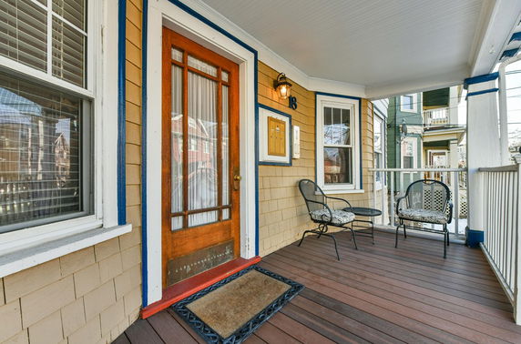 Front view of a house with a wooden entrance door and a small porch area.