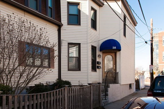 Front view of a two-story house with a blue awning over the entrance.