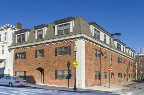Front view of a multi-story brick building with dormer windows.