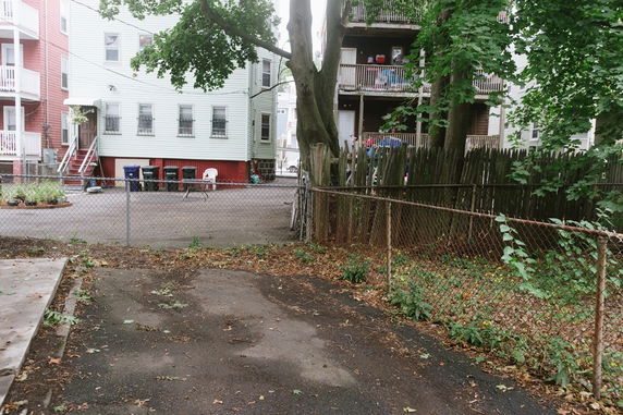 Back view of residential buildings with fences and trees.