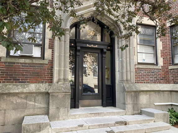 Front view of a brick building entrance with stone steps.