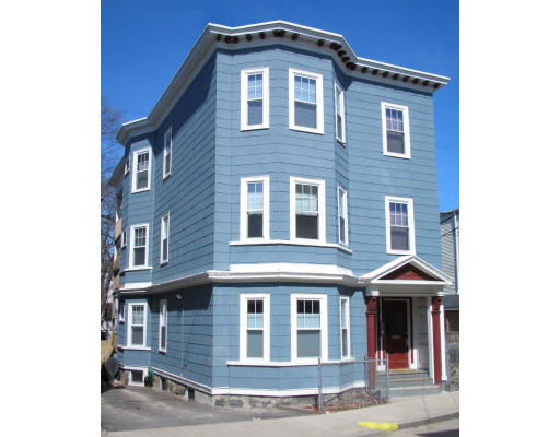 Front view of a three-story house with blue siding and multiple windows.