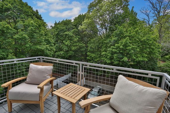 Balcony with chairs overlooking a view of trees.