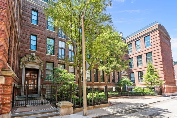 Front view of a multi-story brick building with large windows and decorative entrance.