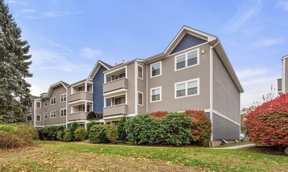 Front view of a multi-story residential building with balconies and gable roof.