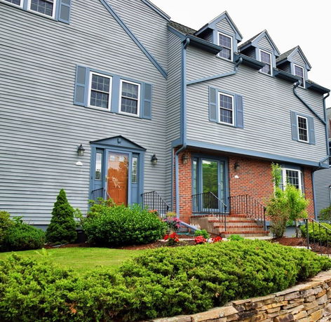 Front view of a multi-story house with a gray exterior and brick accents.