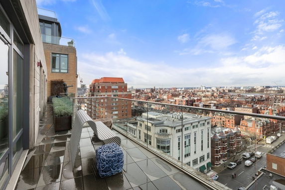 Wide-angle view from a balcony overlooking a cityscape with buildings and streets.