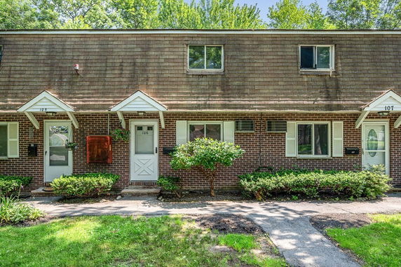 Front view of a two-story brick townhouse with a sloped shingle roof.