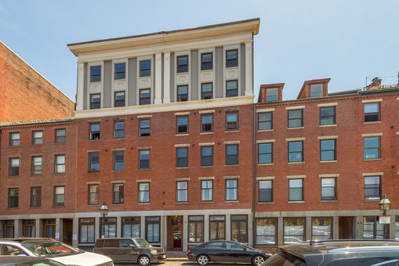 Front view of a multi-story brick building with large windows.