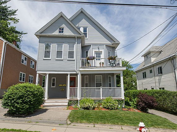 Front view of a multi-story house with a porch and balcony.