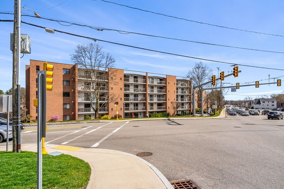 Front view of a multi-story apartment building at a street intersection.